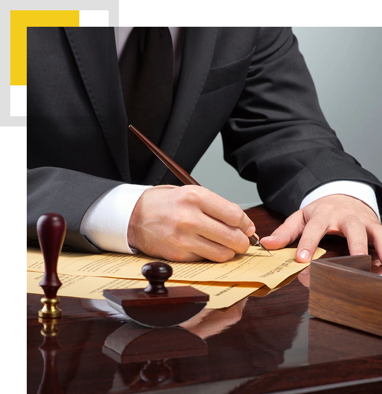 A person in suit writing on paper with a wooden gavel.